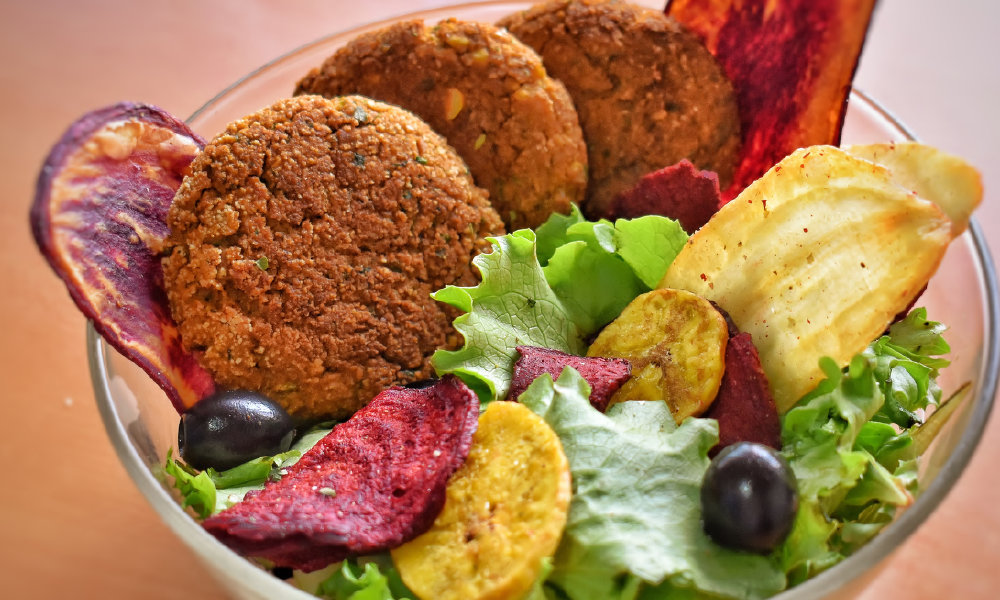 Falafel con ensalada, aceitunas negras y chips de vegetales exóticos